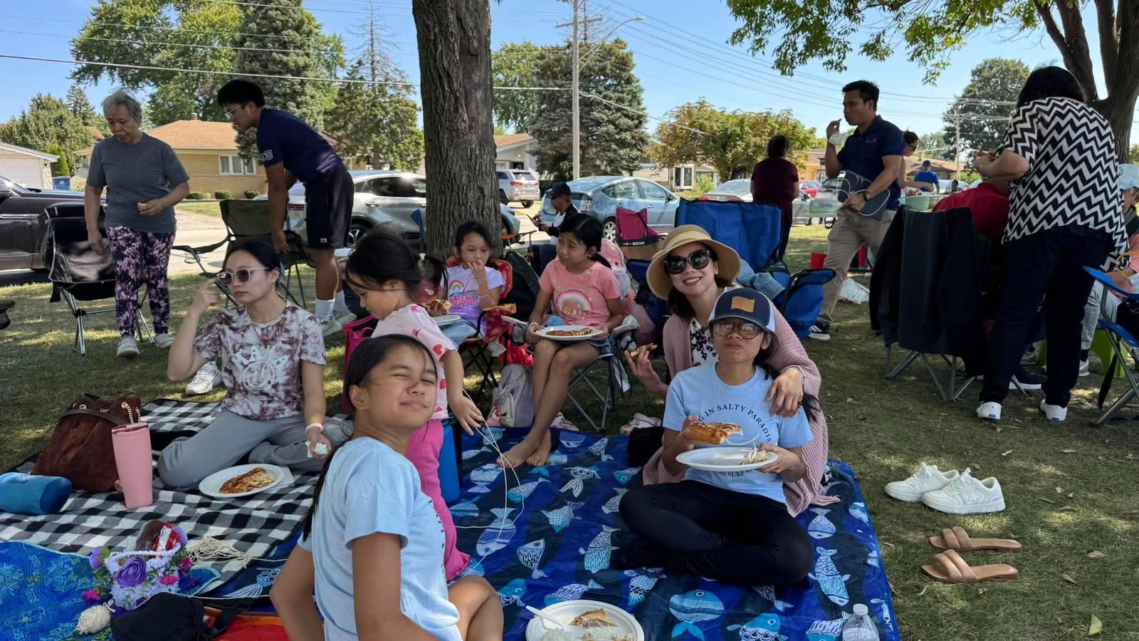 Church family sitting together on picnic blankets under the trees at Lake Opeka